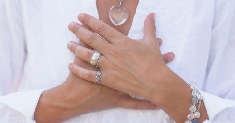 Deux mains posées sur la poitrine, geste d’ancrage et d’auto-apaisement — préparation en sécurité avant une expérience à la psilocybine